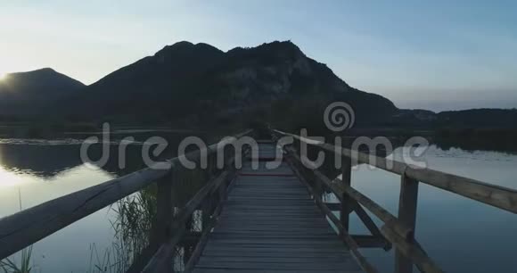 在夏季日出时沿湖上的桥木小径行走欧洲户外绿野野怪视频的预览图