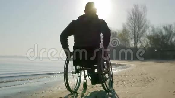 在轮椅上的沙滩上无效的骑行残疾人对未来的信心伙计视频的预览图