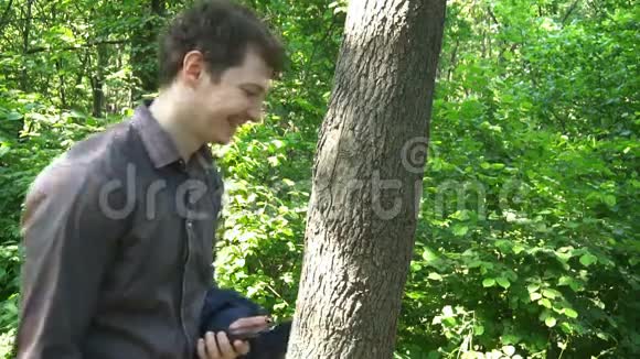 年轻人站在树林里想着什么打电话视频的预览图