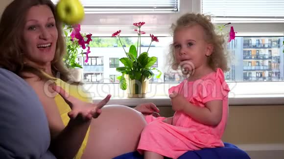 快乐的孕妇和可爱的小女孩一起吃苹果水果视频的预览图