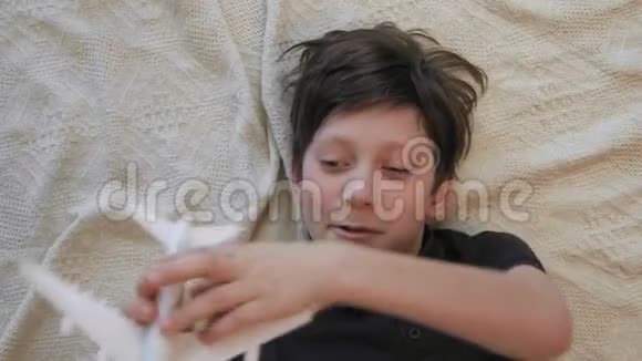 可爱的小男孩躺在地毯上玩玩具飞机的俯视图视频的预览图
