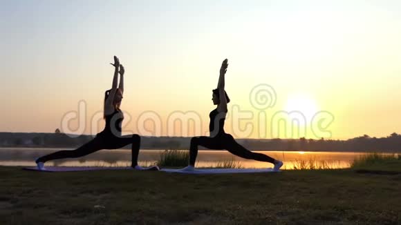两位年轻女性在斯隆莫的夕阳下做瑜伽勇士运动视频的预览图