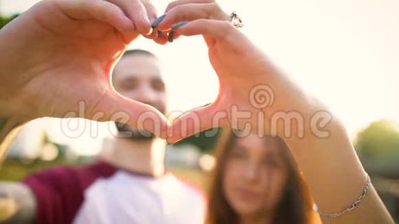 年轻一对相爱的夫妇在日落时用手做心的象征慢动作视频的预览图