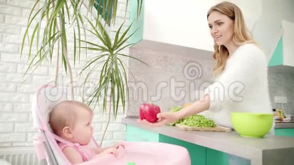 妈妈带着孩子在厨房健康的婴儿食品女人煮蔬菜视频的预览图