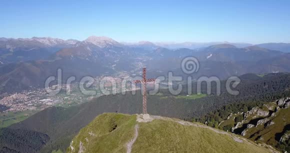 在一个晴朗而蓝色的日子里可以看到塞里亚纳山谷和奥罗比阿尔卑斯山的无人机空中景色山顶的十字架视频的预览图