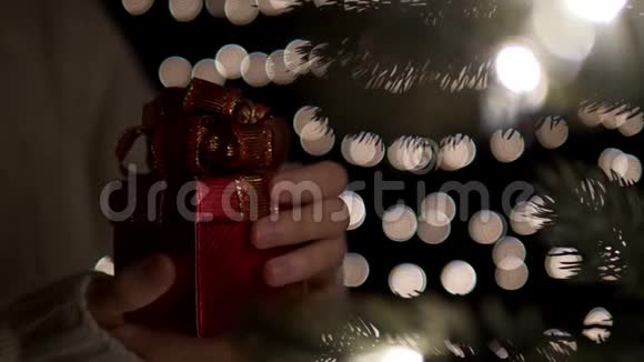 女人在boke灯光背景下打开红色圣诞礼盒视频的预览图