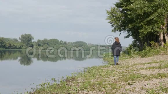 可爱的少女在河岸上钓鱼站在沙滩上拿着鱼竿视频的预览图