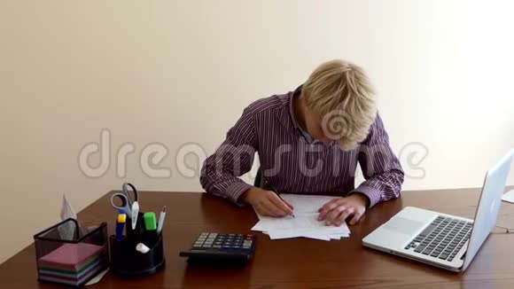男人写文件看计算器坐在办公室的桌子旁视频的预览图