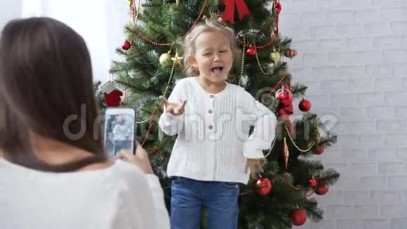 快乐的小女孩在圣诞树附近跳舞和玩猿视频的预览图