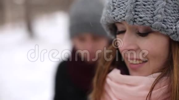 新郎来到新娘身边在大雪纷飞的冬季松林中拥抱并亲吻她浪漫婚礼视频的预览图