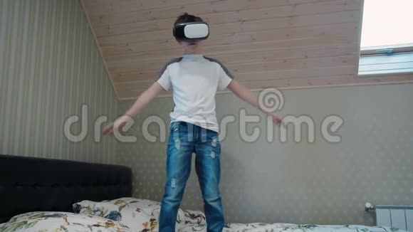 小男孩在飞行模拟器中使用虚拟现实耳机站在床上视频的预览图