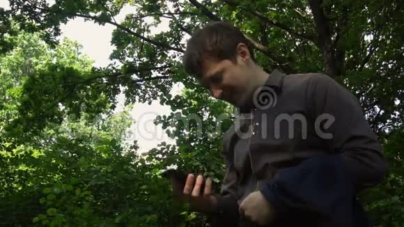 沮丧的男人在树林里对他的智能手机大喊大叫慢动作视频的预览图