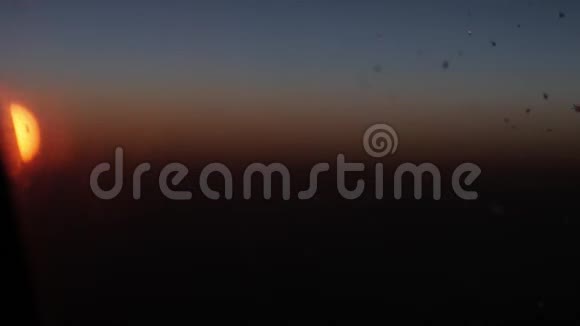 早晨通过客机窗口观看日出黎明时透过飞机窗口俯瞰云景视频的预览图