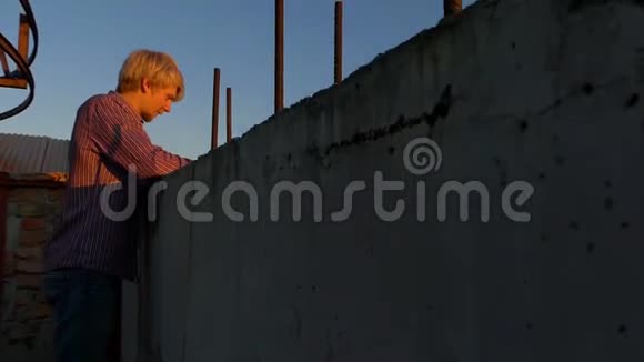 日落时分年轻人在一个高建筑工地上看着他的手机视频的预览图