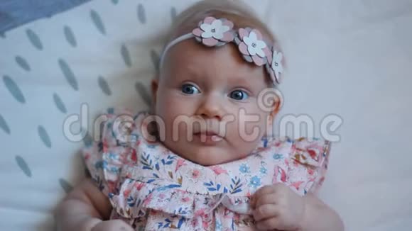 三个月大的蓝眼睛小女孩一个新出生的孩子一个可爱平和体贴的小女孩看着惊讶的微笑视频的预览图