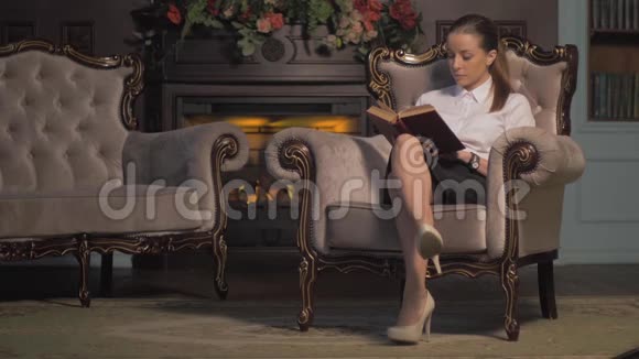 年轻女子在壁炉旁看书翻页视频的预览图