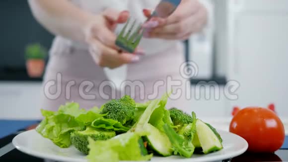 生菜和西兰花和黄瓜手在厨房里混合新鲜的有机绿色沙拉视频的预览图