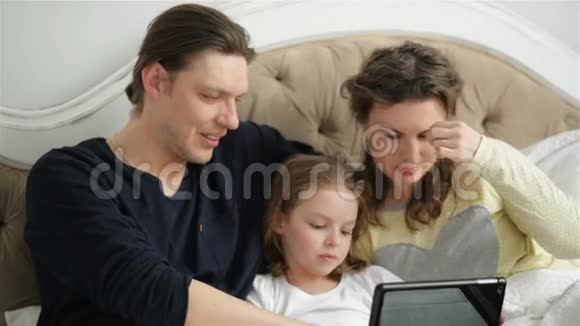年轻家庭躺在床上的特写肖像英俊的父亲在展示和解释一些事情视频的预览图