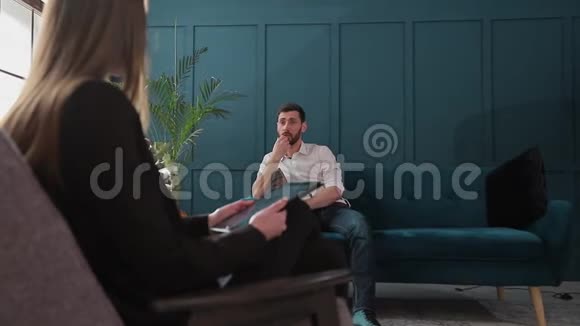 女性心理学家在蓝色办公室内部的心理会话中倾听男性客户的意见视频的预览图