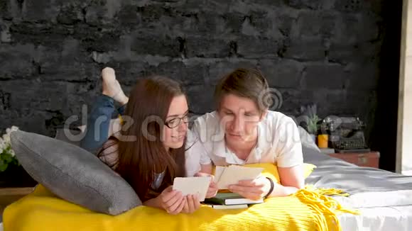 一对夫妇看家庭照片在家里的床上视频的预览图