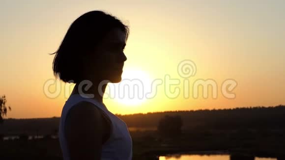 年轻迷人的女人在斯隆莫的灿烂日落中看着浪漫的远方视频的预览图