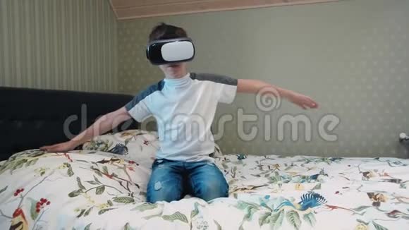 坐在床上的飞行模拟器中使用虚拟现实耳机的小男孩视频的预览图