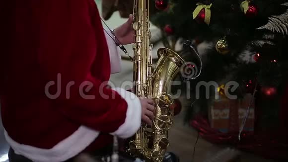 圣诞老人西装革履的萨克斯演奏家在新年树附近演奏圣诞颂歌视频的预览图