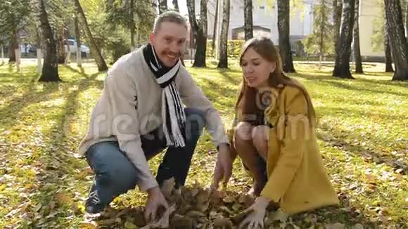 女人和男人在秋天公园里玩着扔树叶的游戏视频的预览图