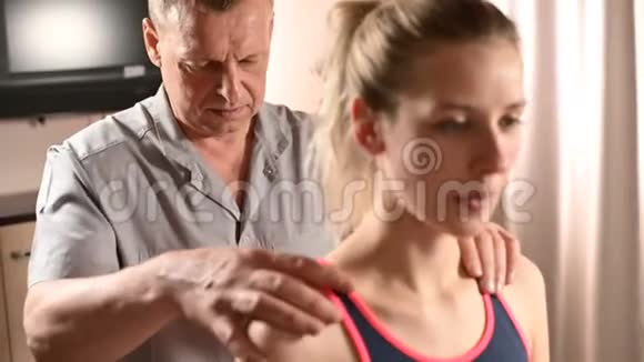 为一位年轻的女病人做健康按摩的男性理疗师手的特写骨病和非传统视频的预览图