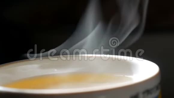涓滴的蒸汽慢慢地从茶杯中升起近距离观看白蒸升光婀娜曲折黑色视频的预览图