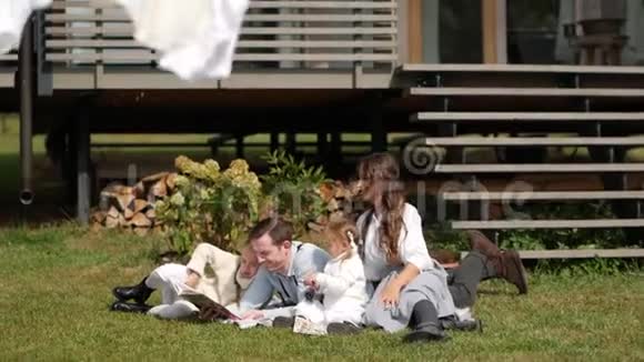 快乐的一家人坐在草地上夏天在草坪上休息慢动作视频的预览图