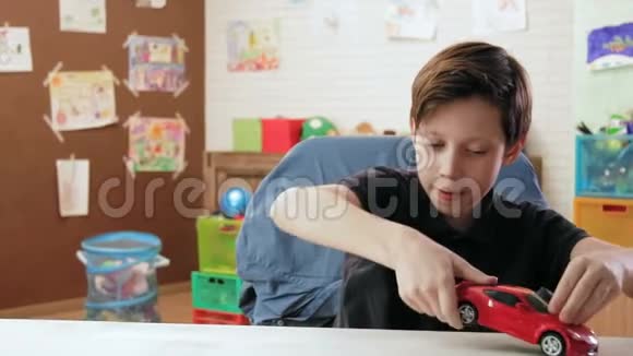 可爱的小男孩在桌子上玩他的红色玩具车视频的预览图
