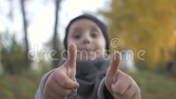 显示一个手势就像手指在顶部微笑的小男孩在公园里玩秋天拇指视频的预览图