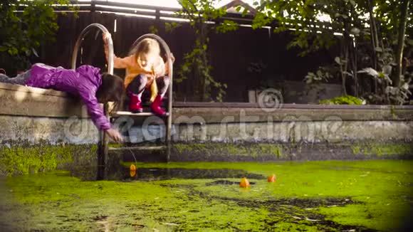 两个女孩在长满浮萍的老游泳池附近玩耍视频的预览图