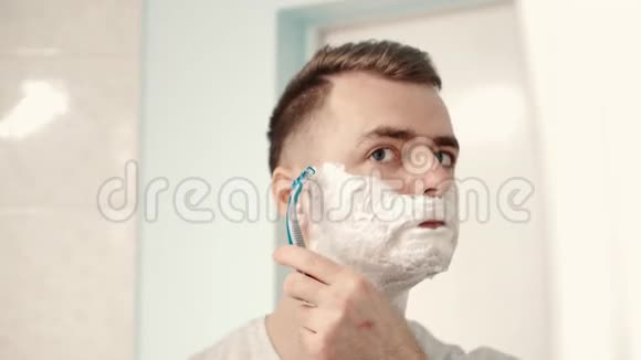 年轻人在浴室的镜子前刮胡子视频的预览图