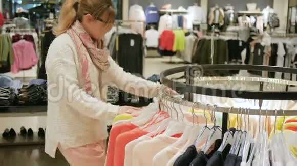 时尚时尚的女人为她的衣柜挑选东西各种五颜六色的衣服挂在木制衣架上视频的预览图