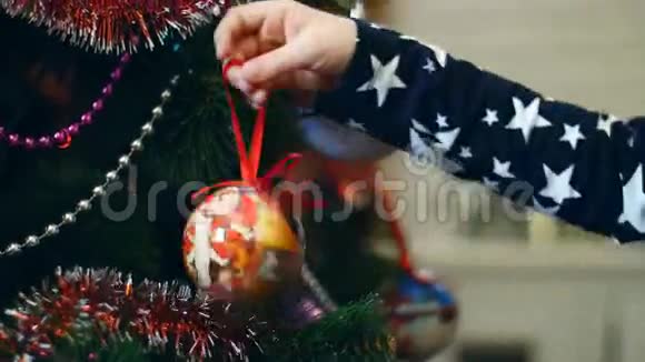 小女孩的双手正在装饰一棵圣诞树上面有鲜艳的圣诞玩具小球视频的预览图