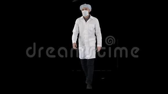 带着面具戴着医疗帽走路的年轻男医生阿尔法频道视频的预览图