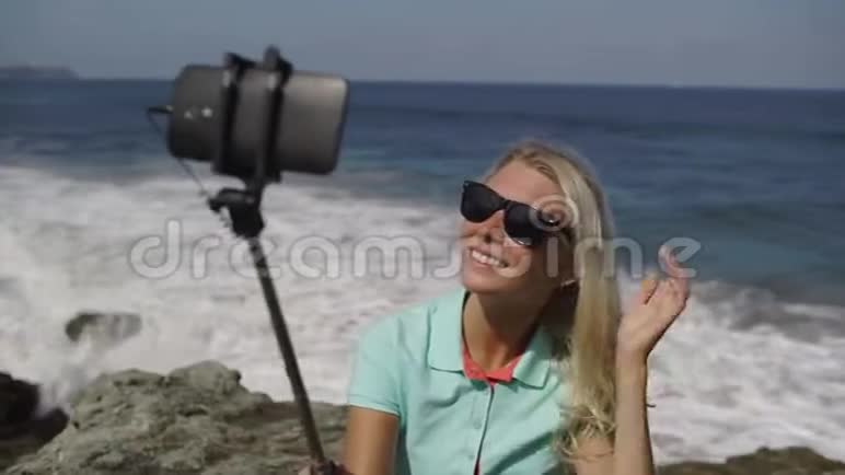 快乐的女人在海滩上的智能手机上拍自拍照片视频的预览图