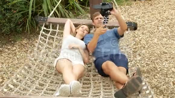 一对夫妇在城市游乐园的热带吊床上放松在相机上自拍4k复制空间视频的预览图