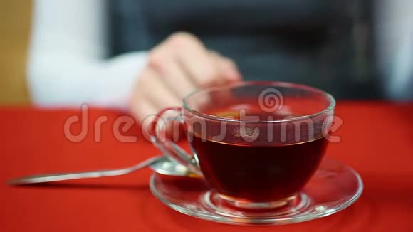 女人在杯子里搅拌精制的糖喝热红茶和朋友见面视频的预览图