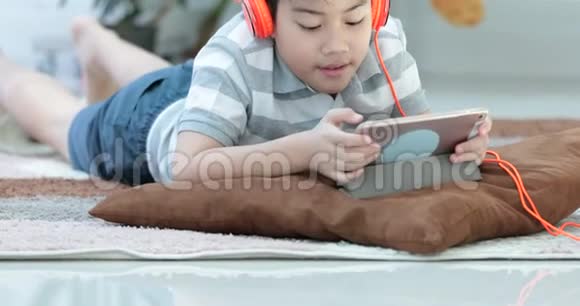 接近亚洲青少年前休息在地板和玩平板电脑与微笑的脸在家视频的预览图
