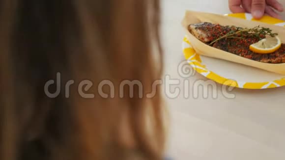 后景年轻女士和服务员用烤鱼摆盘视频的预览图