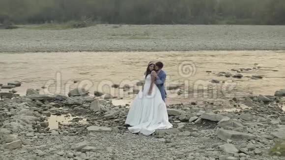 新婚夫妇站在山河附近新郎和新娘相爱视频的预览图