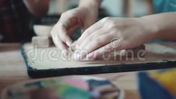 女孩揉捏粘土为她做一个泥塑从事陶器行业女性双手特写视频的预览图