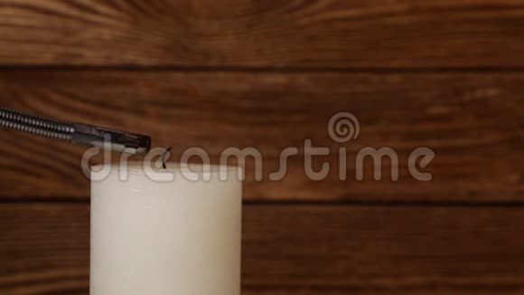 特写白色蜡烛在木头上颤抖的火焰视频的预览图