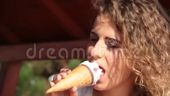 美丽的女孩卷发吃冰淇淋阳光明媚的夏天肖像视频的预览图