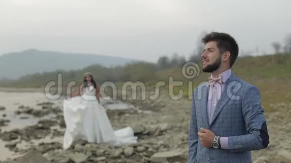 新婚夫妇站在山河附近新郎和新娘相爱视频的预览图