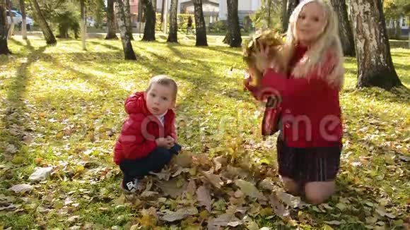 男孩和女孩在秋天公园里玩扔树叶的游戏视频的预览图