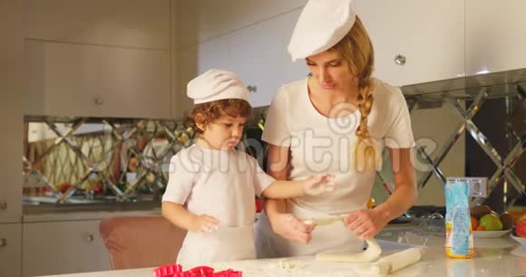 可爱快乐的母亲教儿子在厨房里烤面包的情景那小孩正在用视频的预览图